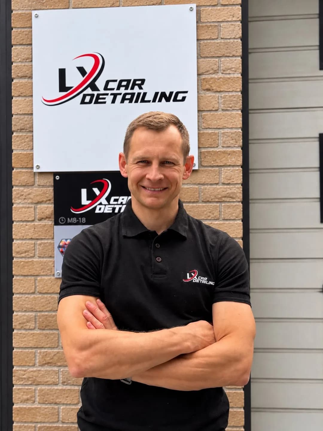 Agris, founder of LX Car Detailing, at the workshop sign at Gaujas iela 20